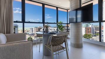Een balkon met een eettafel, stoelen en een bloempot.