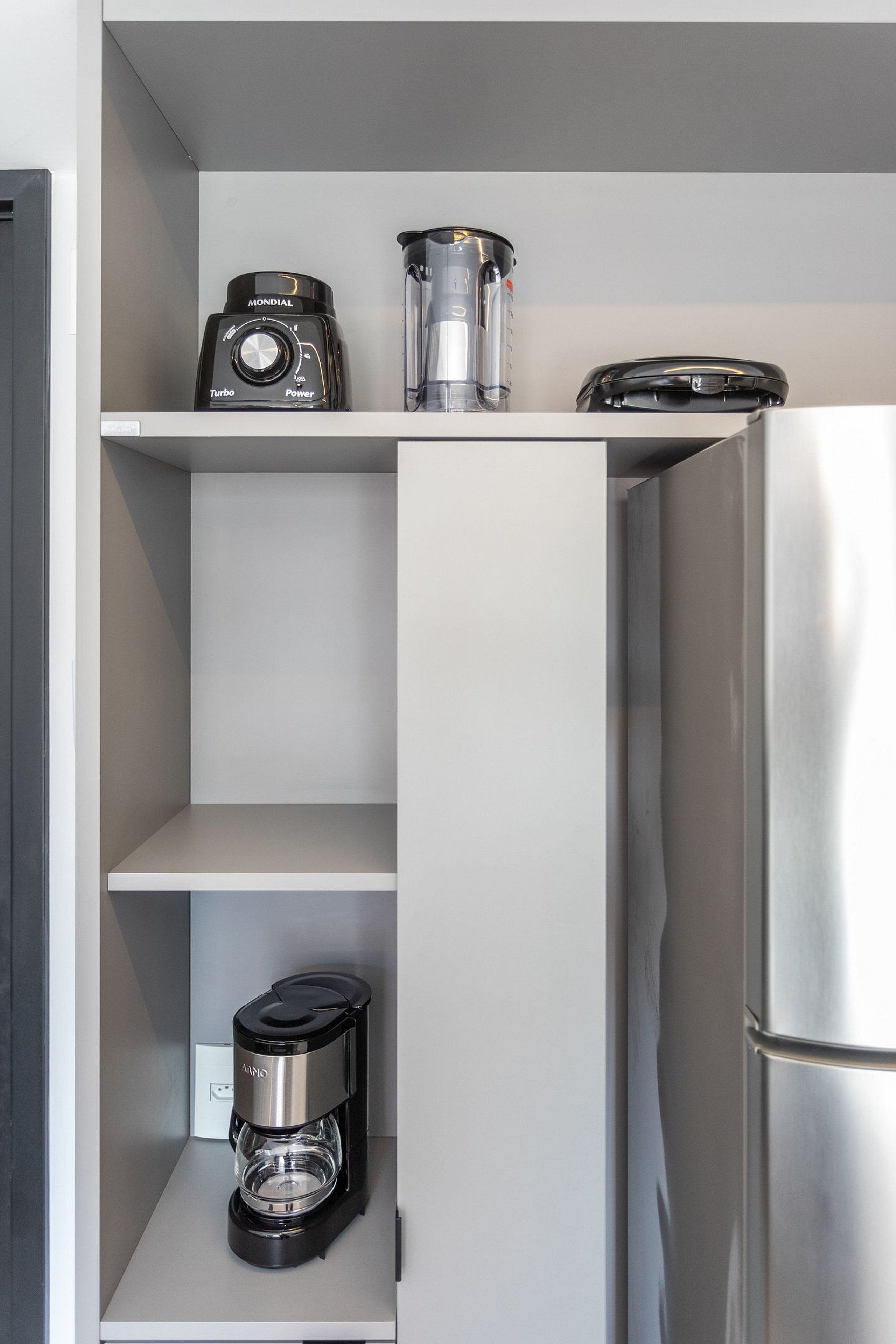 A kitchen with a built-in refrigerator, a coffee maker, and a blender on the shelves.