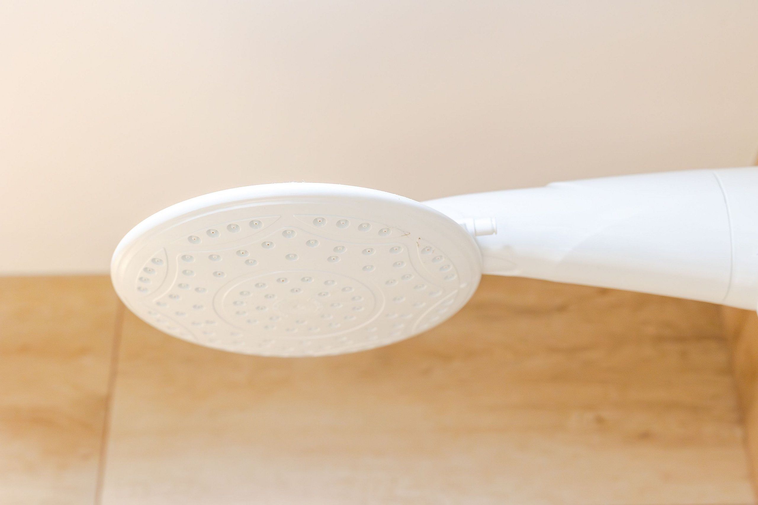 Un cabezal de ducha blanco de mano con una base circular.