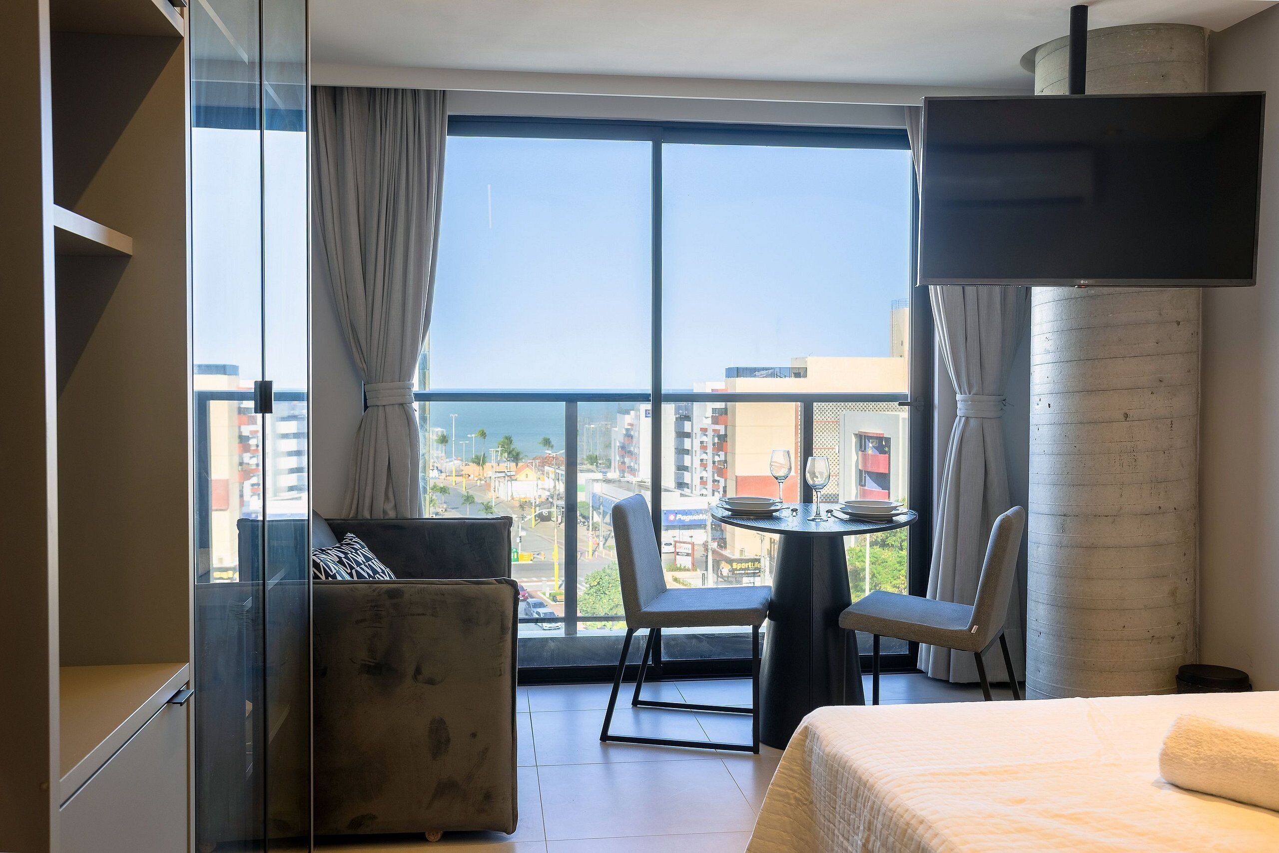 A hotel room with a bed, a sofa, a chair, a small table, and a TV.