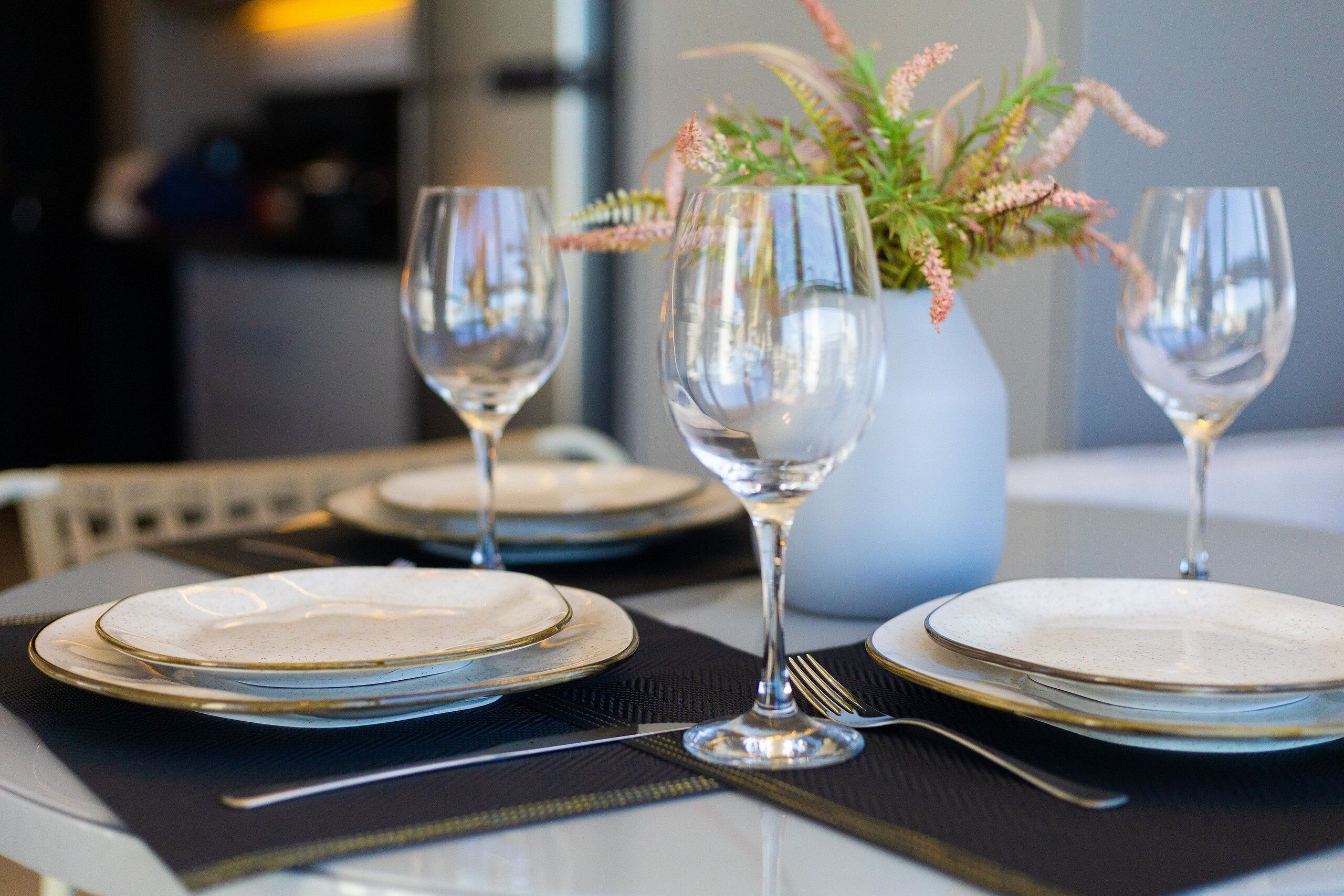 A table set for dining with plates, cutlery, and wine glasses.