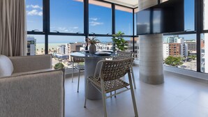 A balcony with a dining table, chairs, and a potted plant. - Way Tambaú - João Pessoa by Carpediem (João Pessoa)