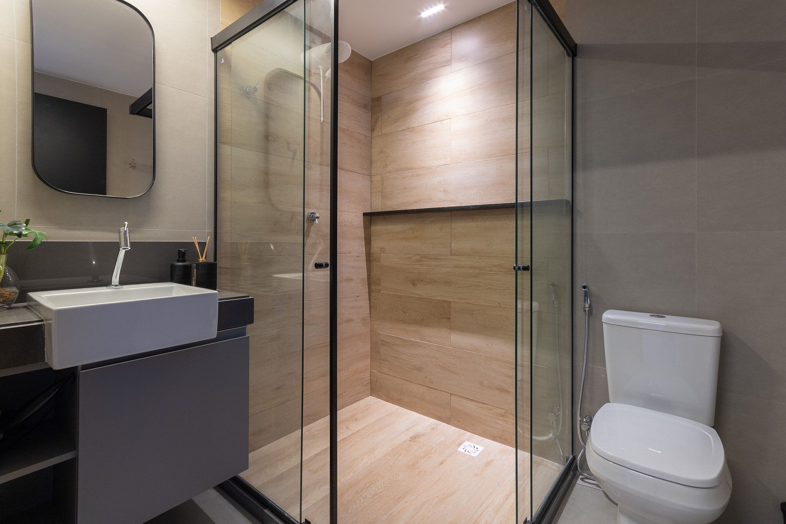 A modern bathroom with a glass shower enclosure, a white sink, and a toilet.