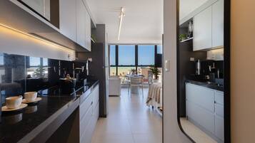 Cocina moderna con encimeras oscuras, armarios blancos y vistas al exterior.