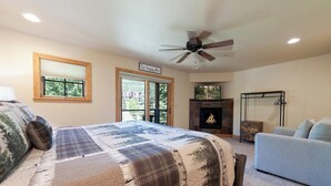 A bedroom with a large bed, a fireplace, a ceiling fan, and a view of the outdoors through a sliding door. - Pet Friendly Black Bear Townhome across from Purg - Views - Free Shuttle (Durango)