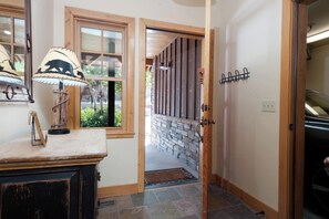 A hallway with a stone wall, wooden door, and a lamp on a wooden surface.