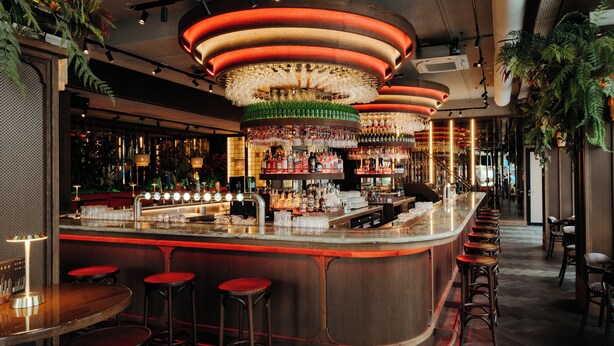 A bar area with a curved counter, multiple stools, and a variety of bottles and glasses. - The Diamond (Amsterdam)