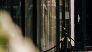 A modern hotel entrance with a revolving door, a glass facade, and a visible sign reading "HOTEL THE DIAMOND." - The Diamond (Amsterdam)