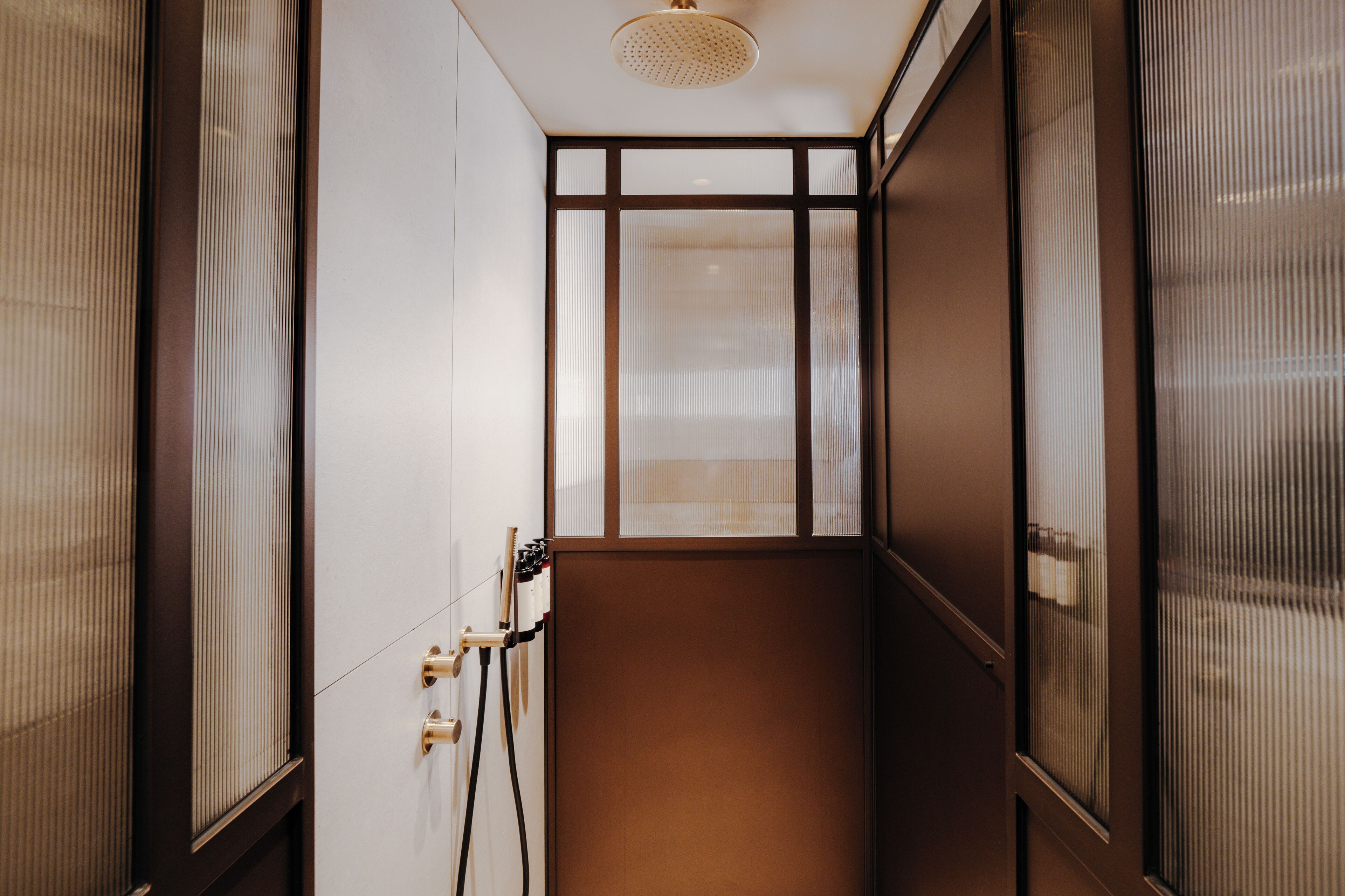 Un pasillo estrecho con una puerta de madera a la derecha y una ventana a la izquierda.