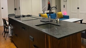 Une cuisine moderne dotée d’un îlot central, de luminaires suspendus et d’un évier encastré.