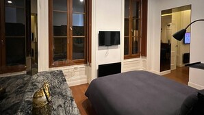 Une chambre à coucher moderne, dotée d’un grand lit, d’un téléviseur à écran plat et d’un tapis à motifs de marbre.