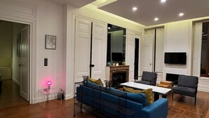 Un salon spacieux avec un canapé bleu, une cheminée et un téléviseur à écran plat.