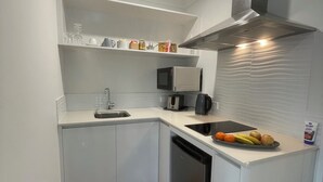 A compact kitchen with white cabinets, a microwave, a coffee maker, and a dish rack. - A cosy private room in Eglinton. (Eglinton)