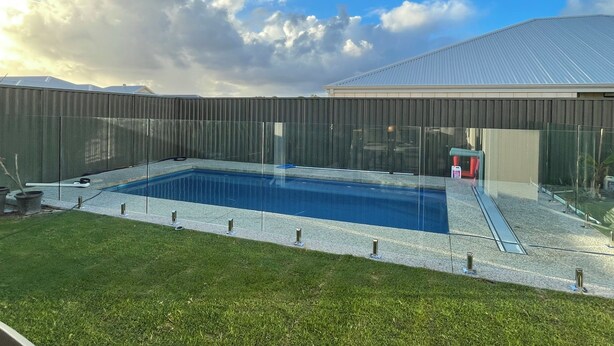 A backyard with a swimming pool, a fenced area, and a building in the background. - A cosy private room in Eglinton. (Eglinton)