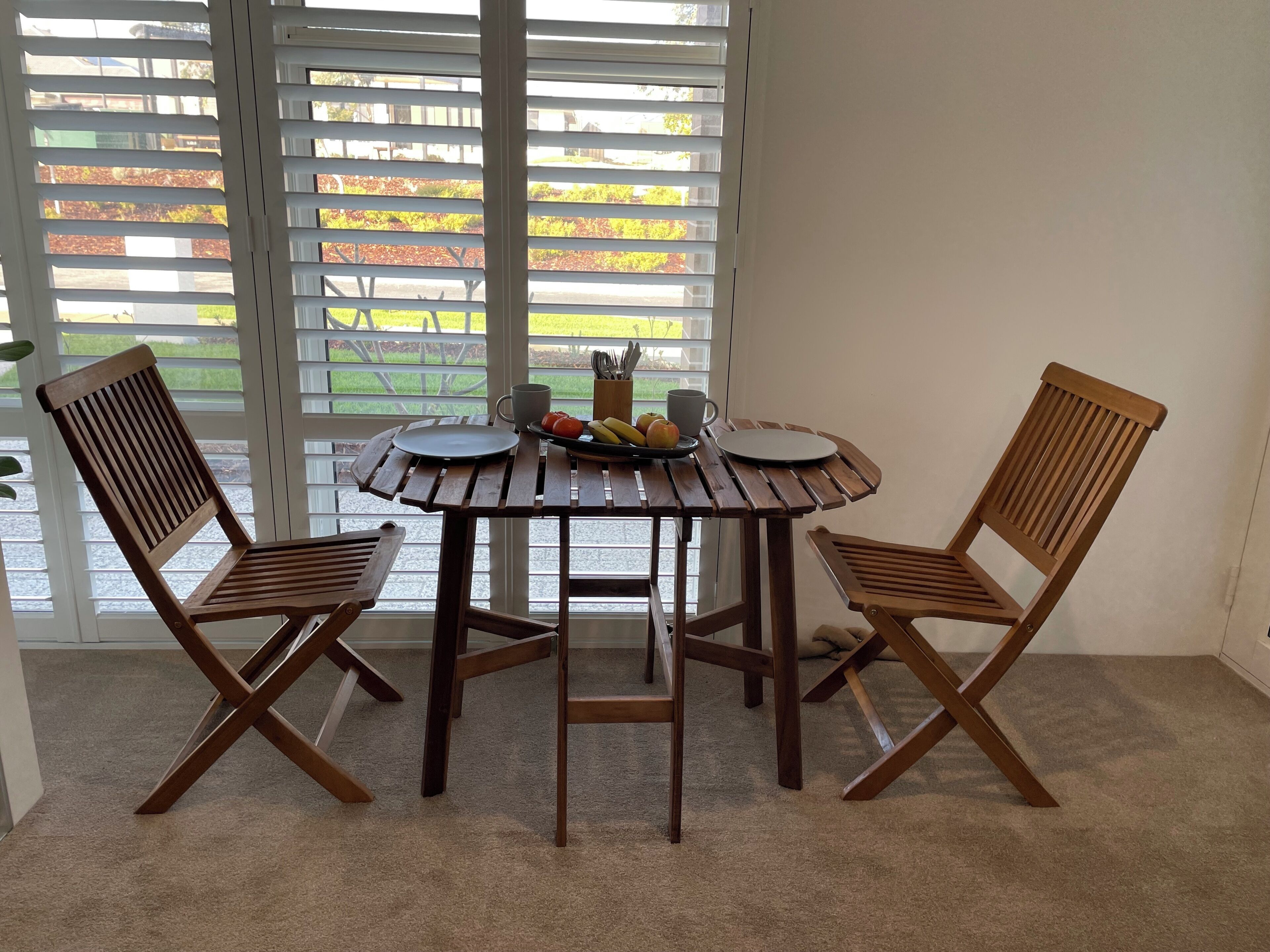 A dining area with a round table and four wooden chairs.