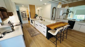 Una cocina moderna con armarios blancos, una isla de madera y un taburete.