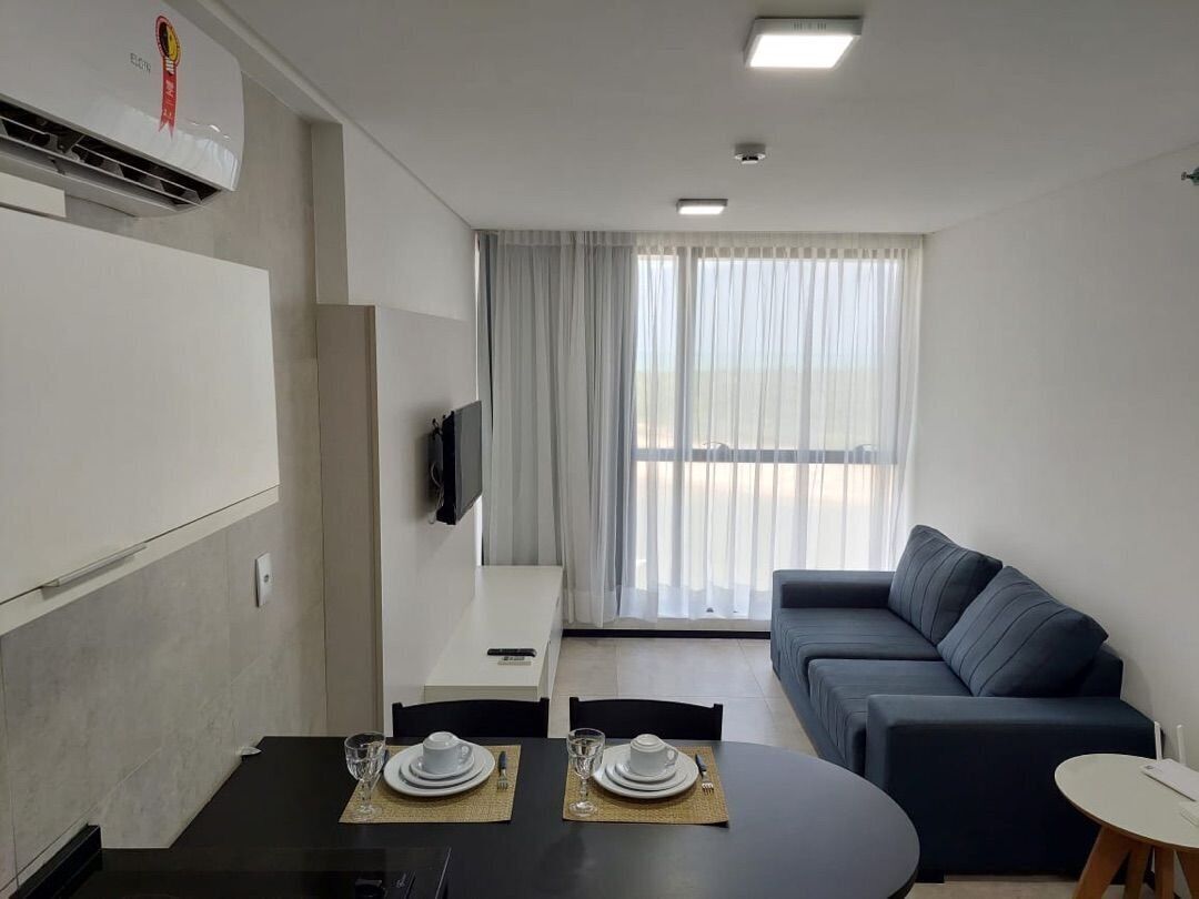 A modern living room with a dining area, a sofa, and a TV.