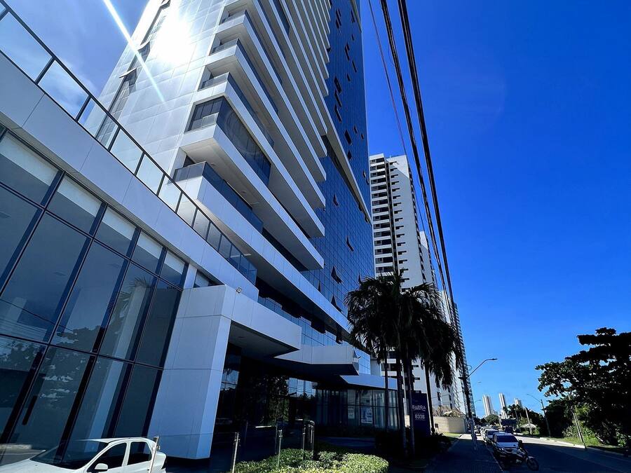 A modern high-rise building with reflective glass windows and a clear blue sky.