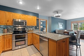 A modern kitchen with wooden cabinets, stainless steel appliances, and a granite countertop. - Short Walk to Lifts & Village Amenities & Private Balcony Overlooks Pool! (Keystone)