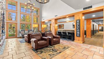 A lobby with a reception desk, leather sofas, a chandelier, and large windows.