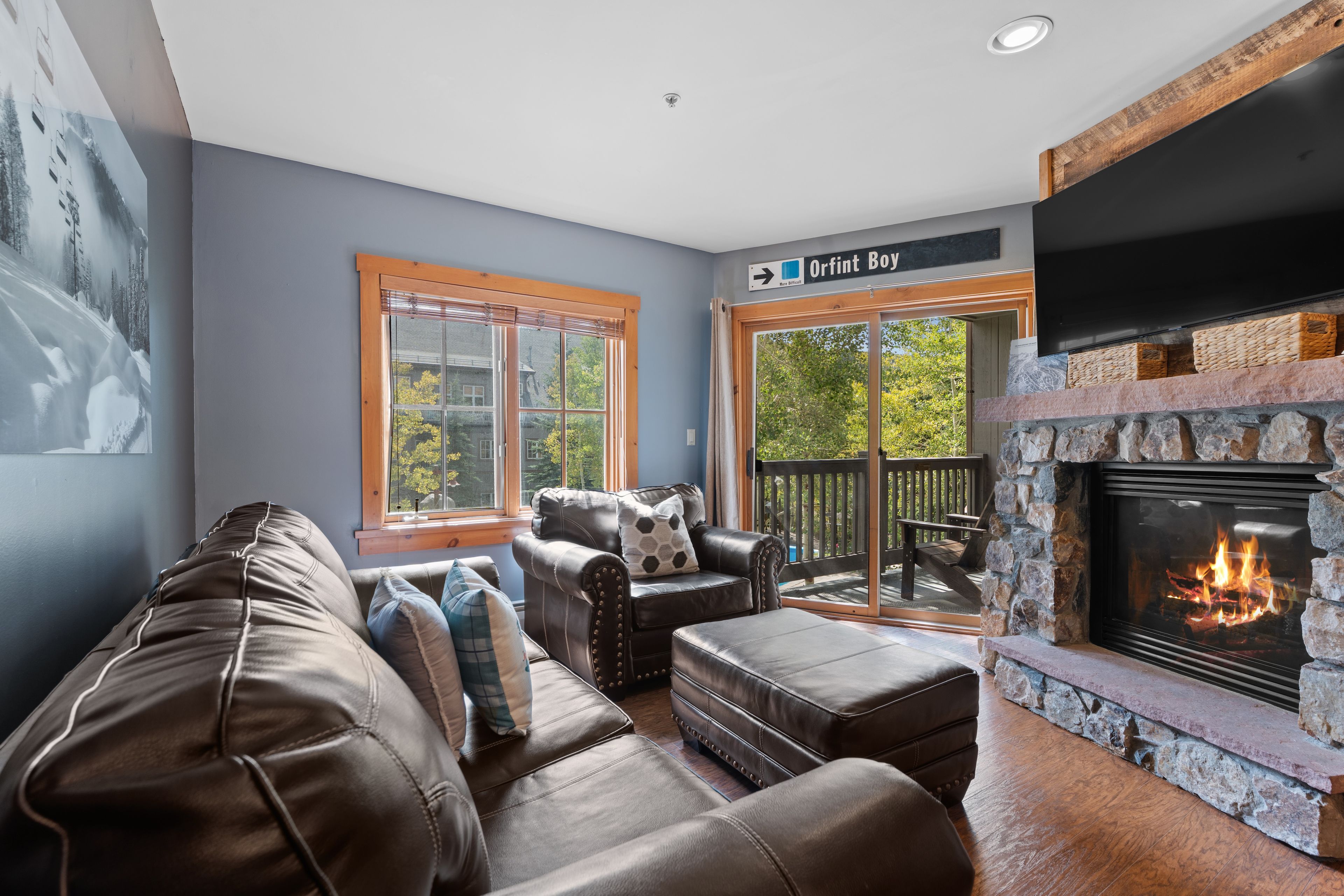 A cozy living room with a fireplace, leather furniture, and a view of the outdoors.