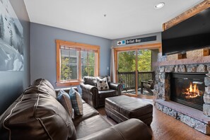 A cozy living room with a fireplace, leather furniture, and a view of the outdoors.