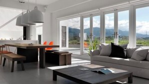 A modern living room with a sofa, coffee table, and dining area with chairs. - Water House (Yilan)