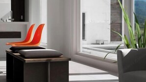 A modern interior with a large window, a wooden table, and two chairs with cushions. - Water House (Yilan)