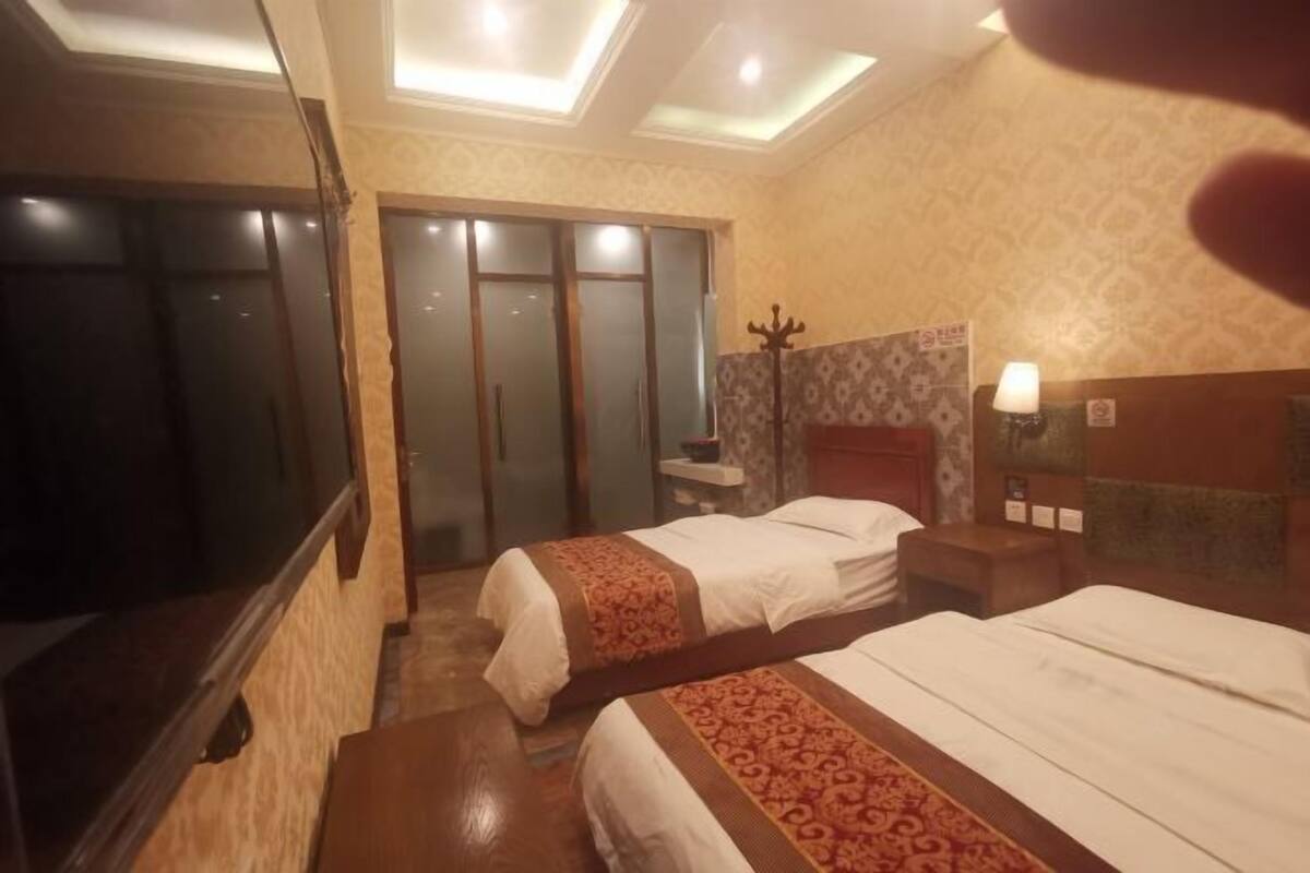 A hotel room with two beds, a mirror, a wardrobe, and a nightstand with a lamp.
