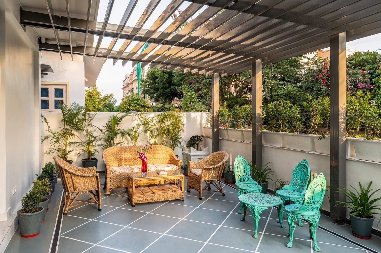 Un patio cubierto con muebles de mimbre, plantas en macetas y una estructura de pérgola.
