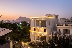 A multi-story building with balconies, a sign reading 'Doc Villa,' and a mountainous backdrop.