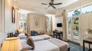 Une chambre d’hôtel avec deux lits, un bureau, une chaise, une télévision et de grandes fenêtres.