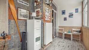 A room with a brick wall, a white radiator, a wooden chair, and a table with a glass. - Apartamenty Sun & Snow Obrońców Westerplatte 8 (Sopot)