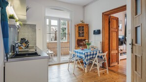 A compact kitchen with a sink, a dining area with a checkered tablecloth, and a wooden cabinet. - Apartamenty Sun & Snow Obrońców Westerplatte 8 (Sopot)
