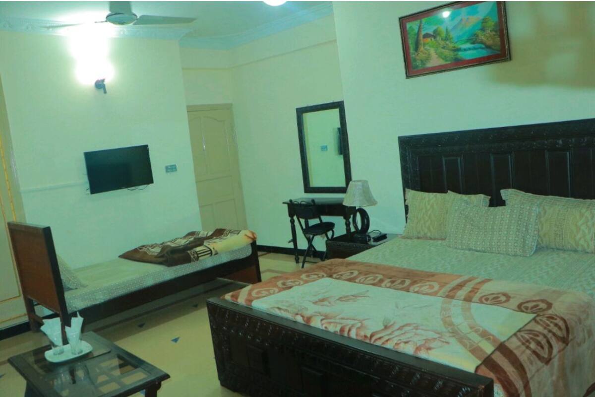 Ein Hotelzimmer mit einem Bett, einem Schreibtisch, einem Stuhl, einem Fernseher und einem Bild an der Wand.