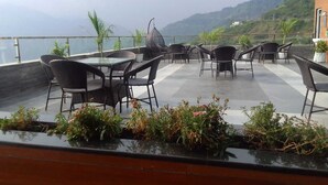 Terraza en la azotea con mobiliario exterior, plantas en macetas y vistas a las montañas.