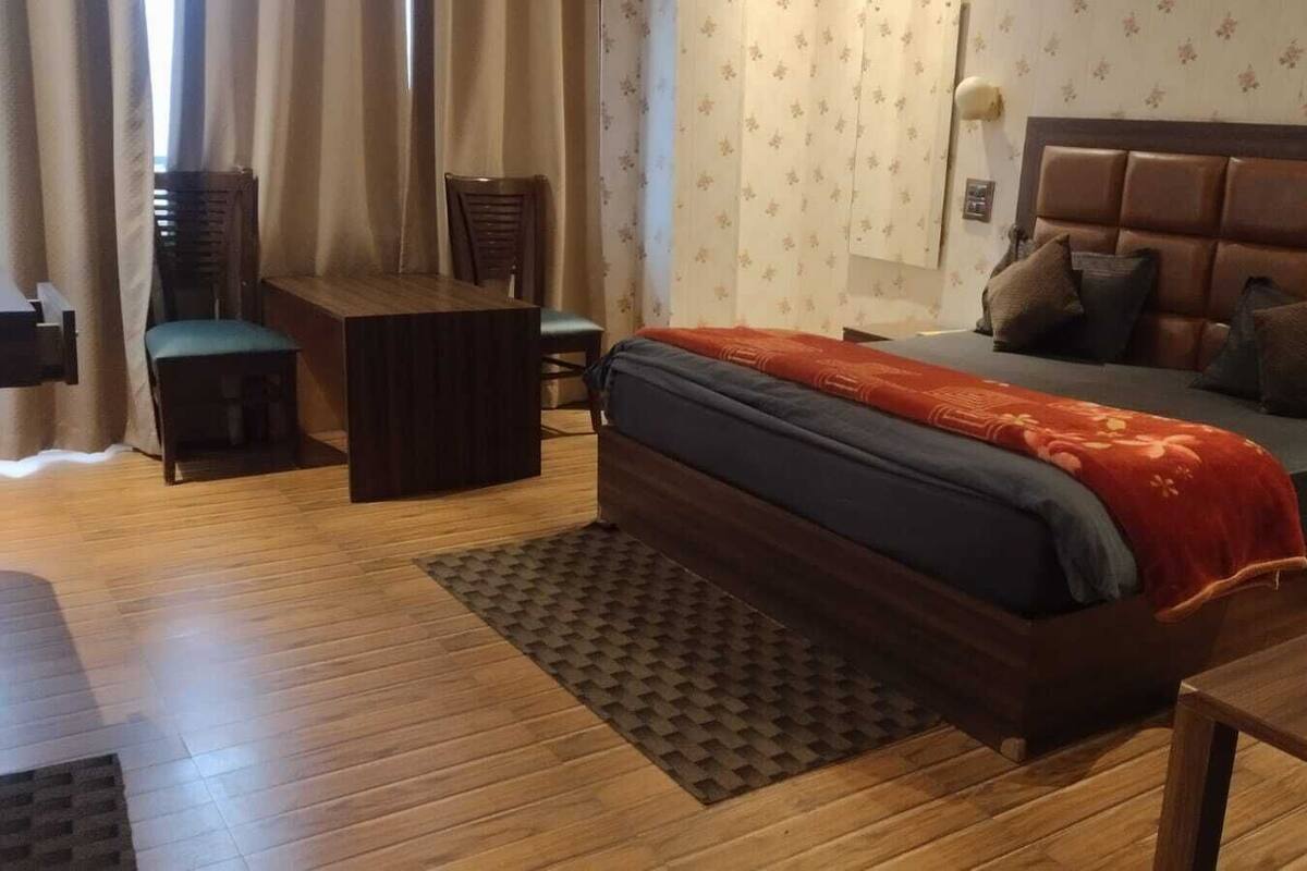 A bedroom with a bed, a desk, a chair, and a window with curtains.