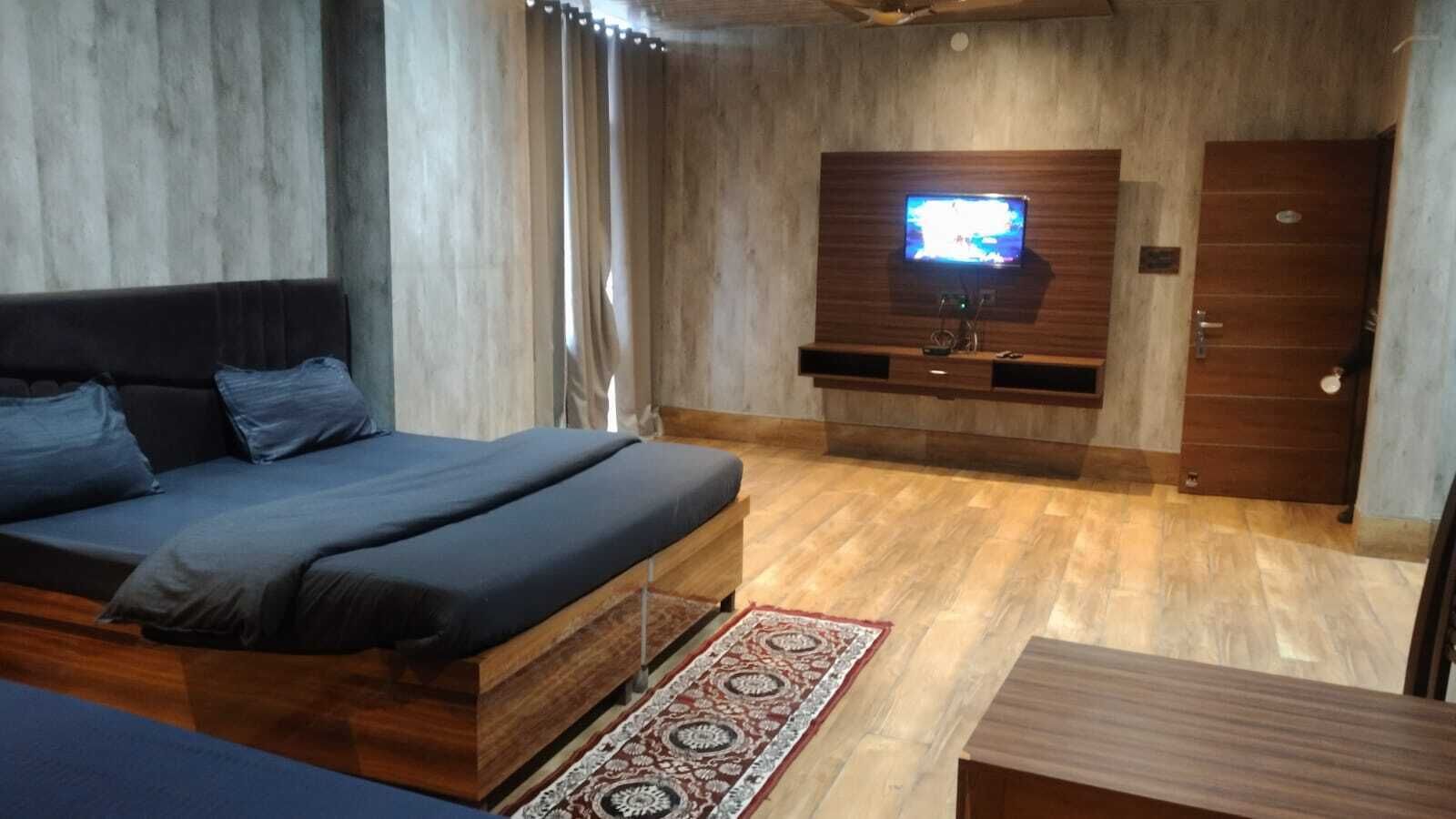 Ein modernes Schlafzimmer mit einem Bett, einem an der Wand montierten Fernseher und einem Holzschrank.