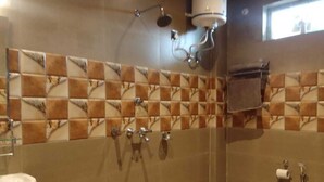 Un baño con ducha, lavamanos e inodoro. Hay un perchero en la pared.