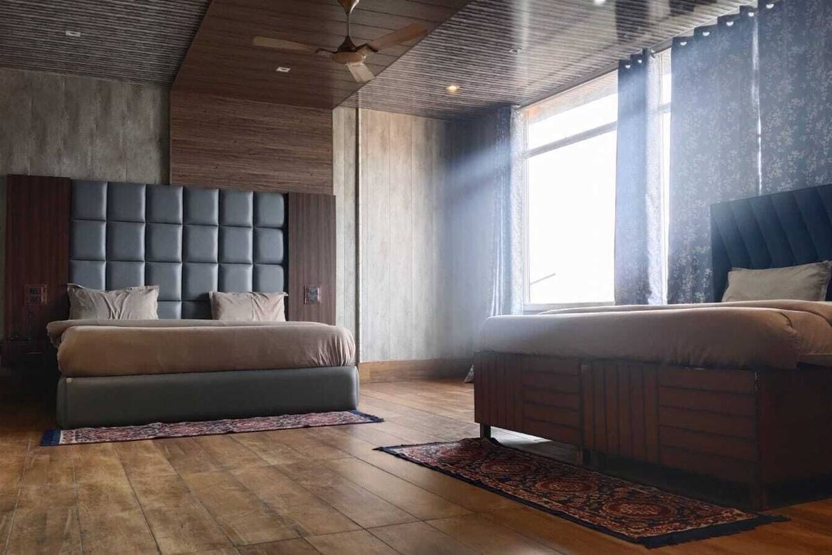 A modern bedroom with a large bed, a smaller bed, and a seating area.