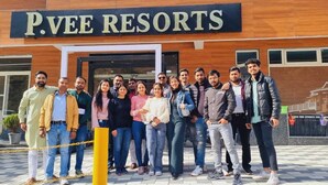Un grupo de personas de pie frente a P.VEE RESORTS.