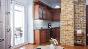 Une cuisine moderne avec des meubles en bois, un mur d’accent en briques, une table à manger agrémentée d’un vase de fleurs et une porte-fenêtre coulissante donnant sur un balcon.