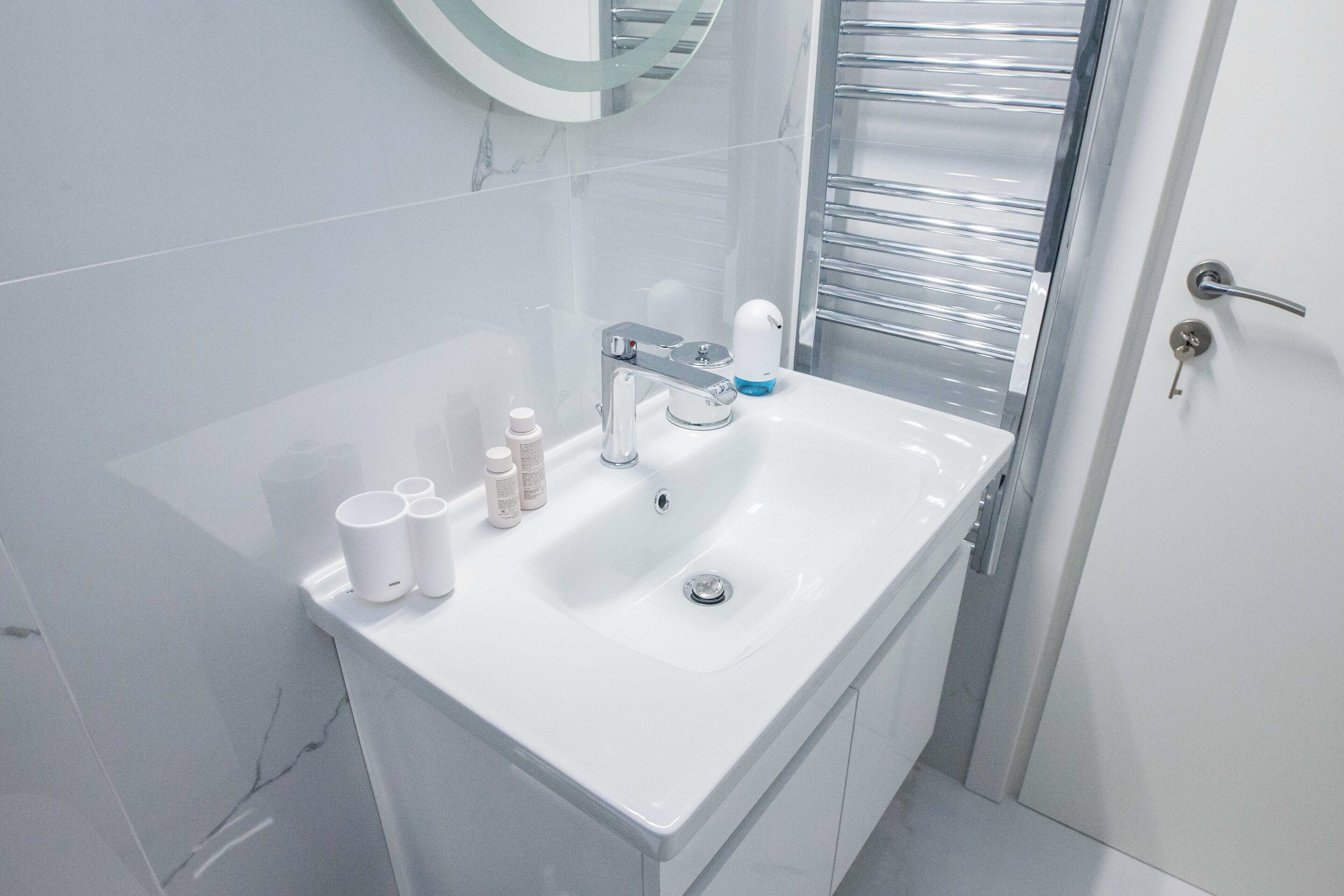 A modern bathroom with a white sink, chrome faucet, and a glass shower enclosure.