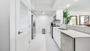 Una cucina moderna con mobili bianchi, elettrodomestici in acciaio inossidabile e pavimento in marmo.