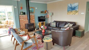 Una sala de estar acogedora con chimenea, sofá de cuero y sillas de madera.