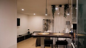 Une cuisine moderne avec un îlot central, des tabourets de bar noirs et des plantes suspendues.