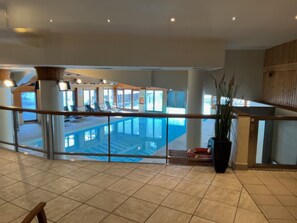 Un espacio interior amplio con una piscina grande, zonas de estar y vistas al exterior.
