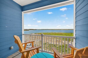 A balcony with a view of a body of water and a distant shoreline. - Luxury Waterfront Townhome | Pool, Boat Slip & Sunset Views (Corpus Christi)
