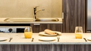 A modern kitchen with a wooden countertop, a stainless steel sink, and bar stools.
