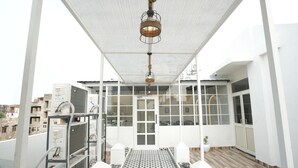 A rooftop terrace with a patterned floor, a hanging light fixture, and a view of the cityscape. - One Earth Elegant Amritsar (Amritsar)